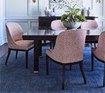 Dining room with a dark wood table, pink patterned chairs, and a blue rug.