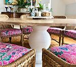 Dining table with white base, wicker chairs, and floral patterned cushions.
