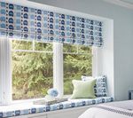 Window seat with patterned blue and white fabric, green pillows, and an outdoor view.