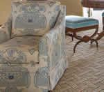 Upholstered armchair with a blue patterned design, tan floor, and an ottoman in the background.