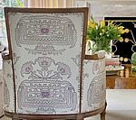 Upholstered armchair with a light-colored floral pattern, wooden frame.