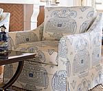 Upholstered armchair with a blue and beige pattern, angled in front of a neutral-toned wall.