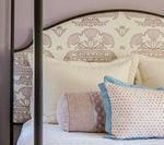 Bed with patterned headboard and pillows.