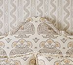 Cream floral headboard with matching wallpaper in neutral tones.