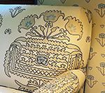Close-up of armchair with cream fabric and patterned design in gray and pale blue.