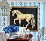 Horse painting on black background, above a table set with flowers and candles. Blue and white wallpaper.