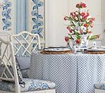Blue and white dining nook with floral arrangement, lattice-back chairs, and checkered tablecloth.