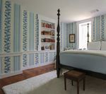 Bedroom with blue patterned wallpaper, four-poster bed, and built-in bookshelves.