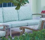 Wooden outdoor bench with patterned teal cushions.