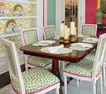 Dining room with wooden table, six patterned chairs, and colorful walls.