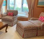 Living room with two leopard-print upholstered armchairs, footrest, and a wooden coffee table.