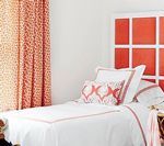 Bedroom with a white bed, coral headboard, and patterned coral curtains.