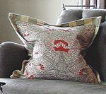 Floral patterned pillow on a gray sofa, with a decorative border.