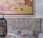 Rattan lantern, patterned headboard, painting of a picnic, glasses, and a glass on a bed.