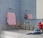 Pink towel on a chrome towel ring in a blue-walled bathroom with a sink, mirror, and decorative items.
