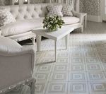 Living room with white sofa, chairs, and table. Patterned light gray tiled floor.