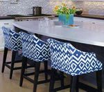 Three blue patterned bar stools at a kitchen island, with flowers in a vase in the background.