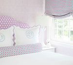 Bedroom with lilac polka dot headboard, pillows, window shade, and white bedding.