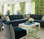 Living room with navy blue sectional sofa, white coffee table, and green patterned curtains.