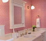 Pink bathroom with white vanity, mirror cabinet, and patterned wallpaper.