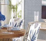 Dining table set with blue accents, chairs with leaf design, and a patterned wall.