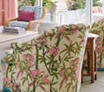 Upholstered dining chair with a cream and pink floral print, next to a white table.