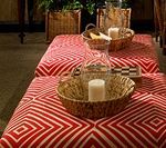 Red patterned ottomans with baskets, candles, and a pitcher.
