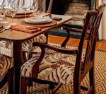 Wooden dining chair with patterned seat; set table in background.