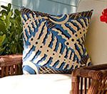 Blue and beige patterned outdoor pillow on a wicker chair.