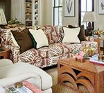 Living room with patterned sofa, brown and cream pillows, wooden coffee table, and beige walls.