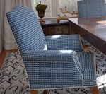 Blue patterned upholstered armchair with white trim, set on patterned rug, near a wooden table.