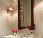 Bathroom with mirror, sconce lighting, and pink flowers.
