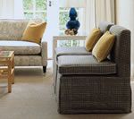 Two patterned sofas with yellow pillows in a living room, near a window, with a vase.