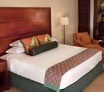 Hotel room with a large bed, brown headboard, white linens, and orange accents.