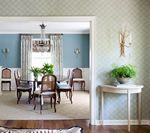 Dining room: blue walls, table with chairs, chandelier, and a side table with a fern.