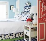 Bedroom with a white bed, blue walls, a white nightstand, and a red patterned curtain.