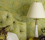 Bedroom with a floral patterned headboard and wall, lamp, and throw pillow.