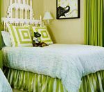 Green and white bedroom with striped bed skirt, patterned pillows, and a framed elephant print.