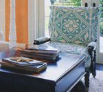 Chair with turquoise patterned cushion, beside a dark wood table with books and a starfish.