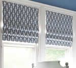 Two windows with blue and white patterned Roman shades.