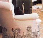 Cream-colored armchair with black patterned base and a black pillow.