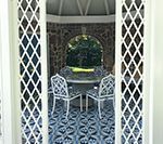 Gazebo interior with table and chairs, visible through diamond lattice. Blue and white patterned floor.