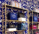 Gold shelves displaying handbags against a blue floral wallpaper backdrop.