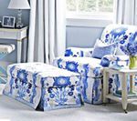 Blue floral armchair and ottoman in a light-filled room, near a small table and window.