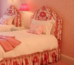Pink floral twin beds in a pink room, with lampshade, wallpaper, and bedding.