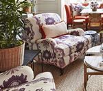 Living room with patterned armchairs, red chairs, and a round table.