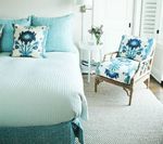 Bedroom with a bed, chair, and side table. Turquoise and white decor with floral accents.