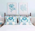 Bedroom with blue decor: bed with floral pillows, framed art of coral on wall.
