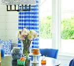 Dining room with blue and white decor; floral arrangement on a table near a window.