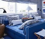Blue and white bedroom with gingham wallpaper, a tufted daybed, and a small table.